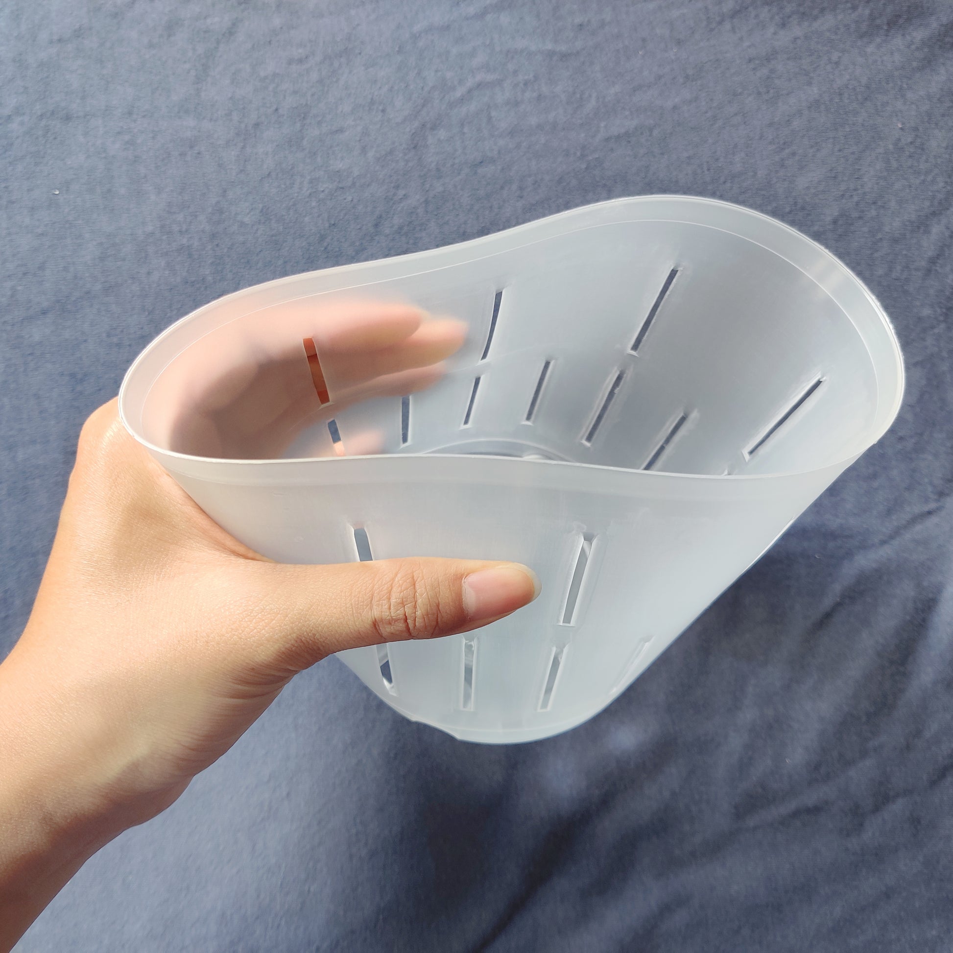 hand squeezing a flexible plant pot, showing the range of flexibility
